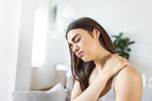 Tired woman massaging stiff sore neck, tensed muscles fatigued from computer work in incorrect posture while feeling hurt joint shoulder back pain ache. Fibromyalgia concept photo