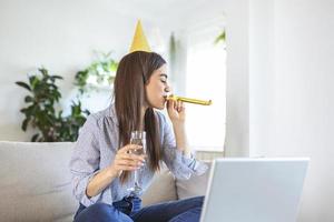 copie la foto espacial de una joven alegre que tiene un evento de celebración de cumpleaños con un amigo a través de una videollamada. ella está haciendo un brindis de celebración con una copa de vino blanco hacia la cámara del portátil.