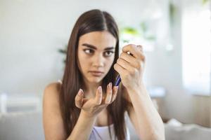 Woman using lancelet on finger. woman doing blood sugar test at home in a living room. photo