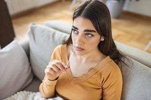 woman using cotton swab while doing coronavirus PCR test at home. Woman using coronavirus rapid diagnostic test. Young woman at home using a nasal swab for COVID-19. photo