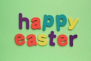 Happy Easter colored lettering on green background. Holiday spring compostion concept. Creative idea for greeting card, poster, banner, invitation, web sale. Top view, flat lay photo