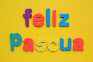 Feliz Pascua, Happy Easter on spanish colored lettering on yellow background. Holiday spring compostion concept. Creative idea for greeting card, poster, banner, invitation. Top view, flat lay photo