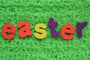 Easter colored lettering on green grass background. Holiday spring composition concept. Creative idea for greeting card, poster, banner, invitation, web. Top view, flat lay, close up photo