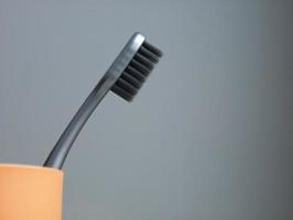 elegante cepillo de dientes gris en un vaso amarillo. lugar para texto foto