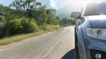 vista frontal del coche que circula por la carretera asfaltada para el viaje. con la naturaleza de los árboles y la hierba al lado de la carretera. bajo el cielo azul. foto