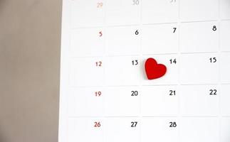 forma de corazón rojo en la fecha del día 14 en el calendario. día de San Valentín foto