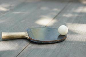 bucles de tenis de mesa y raqueta en mesa de madera foto