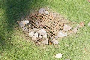 sewer in the lawn has a steel grate. photo