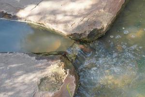 The water in the stream flows through the rocks. photo