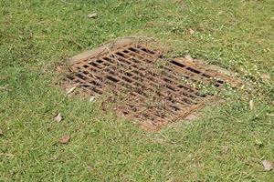 sewer in the lawn has a steel grate. photo