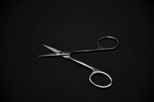 Manicure set on a black background. Scissors and nail tongs. Iron scissors and nail clippers. photo