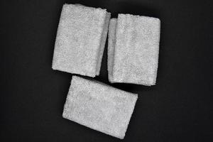 Three gray towels on a black background. Terry cloths for wiping furniture. Towels on a black background. photo