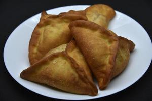 empanadas de carne en un plato blanco. Belyashi deliciosos pasteles de carne sobre un fondo negro. foto