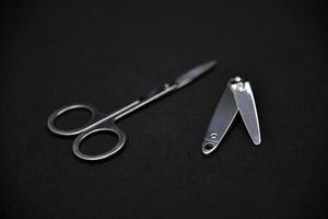 Manicure set on a black background. Scissors and nail tongs. Iron scissors and nail clippers. photo