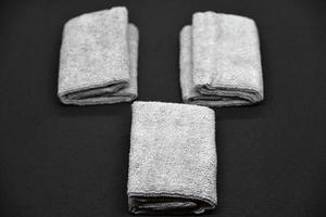 Three gray towels on a black background. Terry cloths for wiping furniture. Towels on a black background. photo