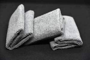 Three gray towels on a black background. Terry cloths for wiping furniture. Towels on a black background. photo