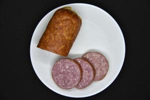 Delicious meat sausage on a white plate. Sliced ham. Slices of meat. photo