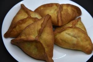 empanadas de carne en un plato blanco. Belyashi deliciosos pasteles de carne sobre un fondo negro. foto