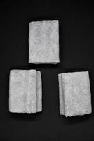 Three gray towels on a black background. Terry cloths for wiping furniture. Towels on a black background. photo