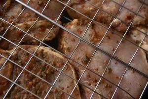 Raw pickled pork meat in an iron mesh. Barbecue grilling net. Delicious raw pork meat. photo