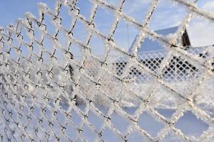 Snow frost on the iron fence of the fence. Mesh netting. Snow patterns on iron. photo