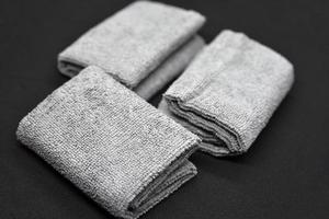 Three gray towels on a black background. Terry cloths for wiping furniture. Towels on a black background. photo