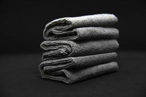 Three gray towels on a black background. Terry cloths for wiping furniture. Towels on a black background. photo