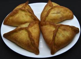 empanadas de carne en un plato blanco. Belyashi deliciosos pasteles de carne sobre un fondo negro. foto