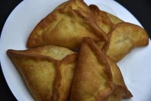 Meat pies on a white plate. Belyashi. Delicious meat pies on a black background. photo