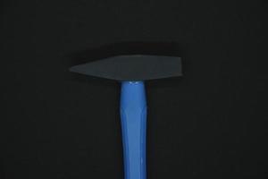 Construction hammer on a black background. A carpenter's hammer with a blue handle on a black background. photo