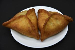 empanadas de carne en un plato blanco. Belyashi deliciosos pasteles de carne sobre un fondo negro. foto