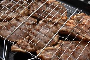 carne de cerdo cruda en escabeche en una malla de hierro. red para asar a la parrilla. deliciosa carne de cerdo cruda. foto