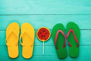 Flip flops and candy on blue wooden background. Top view. Mock up. Copy space. Summer beach holiday. photo