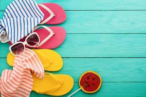 Summer accessories. Flip flops, sunglasses, towel, red cap and oranges on blue wooden background. copy space. photo