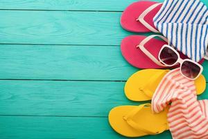 Pink flip flops with candy and copy space on blue wooden background. Top view photo