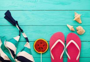 Pink flip flops with candy and copy space on blue wooden background. Top view photo