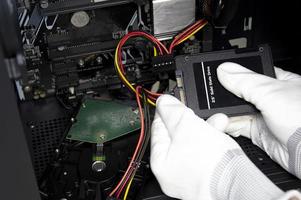 The mechanic is connecting the wires to the 2.5 inch SSD hard drive. photo