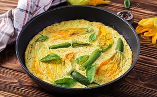 tortilla al horno con flores de calabacín en pan sobre fondo de madera. foto