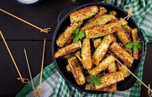 Baked zucchini sticks with cheese and bread crumbs. Vegan food. Vegetarian cuisine. Top view photo