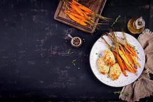 zanahorias orgánicas al horno con tomillo y chuleta, carne de pollo con albóndigas y calabacín. comida dietetica. vista superior foto