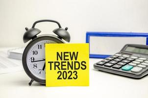 alarm clock and yellow sticker with the text TRENDS 2023. Business concept photo