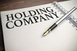 holding company words with pen and wooden background photo