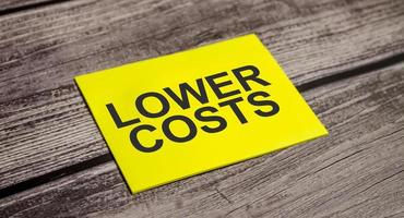 lOWER COSTS Text on business paper on office table photo