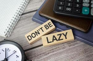 alarm clock, calculator, notebook and wooden blocks with the inscription - don't be lazy photo