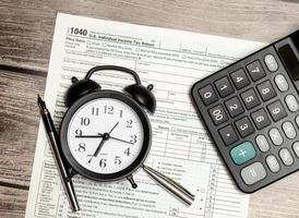 Top view tax form 1040 with pen, calculator and black alarm clock. tax time. financial document. photo