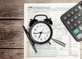 Top view tax form 1040 with pen, calculator and black alarm clock. tax time. financial document. photo