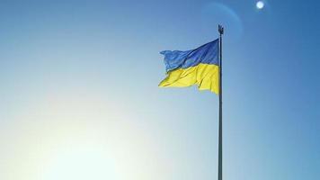 Slow-Motion-Flagge der Ukraine weht im Wind vor einem wolkenlosen Himmel bei Tagesanbruch. Das ukrainische Nationalsymbol des Landes ist blau und gelb. Flaggenschlaufe mit detaillierter Stoffstruktur. video