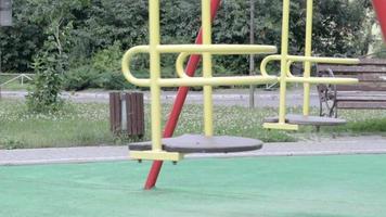 eine leere, menschenleere, metallgelbe schaukel im hof von wohnhäusern im freien schaukeln, sich hin und her bewegend. einfache Freischaukel für Kinder draußen. video