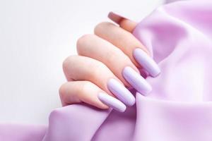 manos de niña con una manicura violeta suave. foto