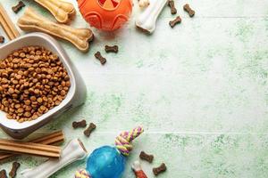 A bowl with dog food, dog treats and toys on a wooden floor. photo